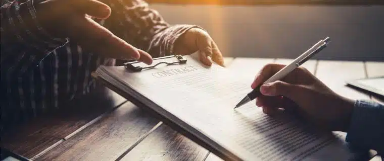 Two people reviewing contract with pens in hand